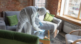 Coronavirus Pandemic. A disinfector in a protective suit and mask sprays disinfectants in house or office. Protection agsinst COVID-19 disease. Prevention of spreding pneumonia virus with surfaces.