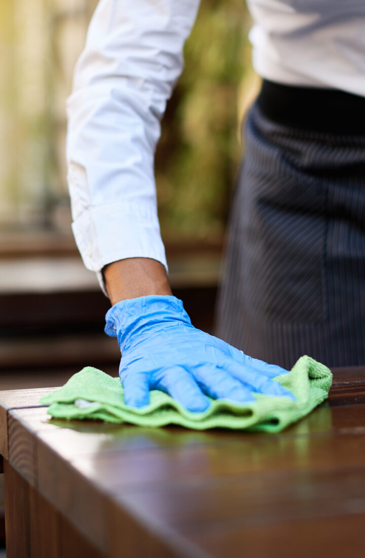 Close-up of waitress cleaning tables with disinfectant. Close-up of waitress disinfecting tables at outdoor cafe during coronavirus epidemic.