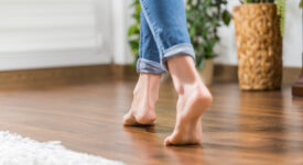 Floor heating. Young woman walking in the house on the warm floor. Gently walked the wooden panels.