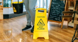 Worker placing wet floor sign after mopping Worker placing wet floor sign after mopping the floor