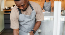 Vertical shot of modern young cafe workers starting workday with cleaning furniture and making notes