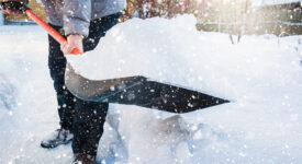 Snow removal. Man clearing snow by shovel after snowfall. Outdoors.