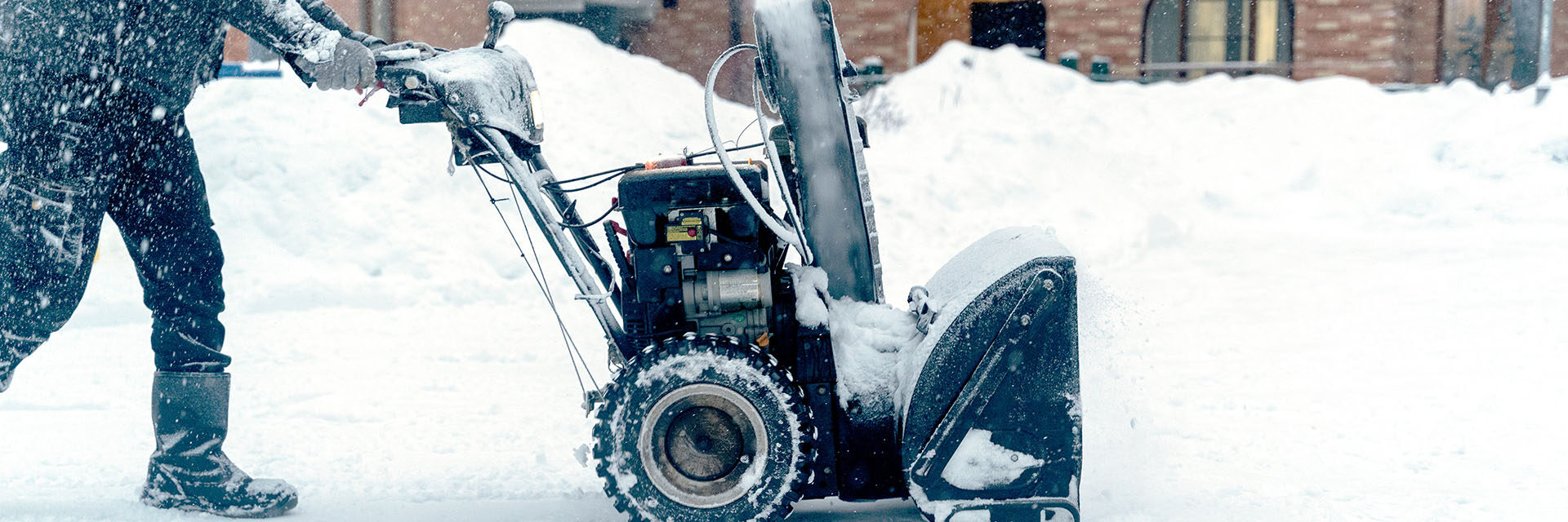 Manual Turbine Snowplow with Motor driven by an Operator dressed in Red during a day with a Heavy Snowfall.