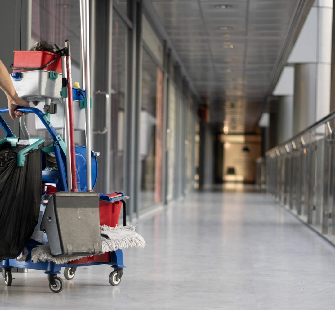 An employee pulls a trolley for cleaning offices. Woman cleaner is engaged in work. An employee pulls a trolley for cleaning offices. Woman cleaner is engaged in work. Shopping center place for text