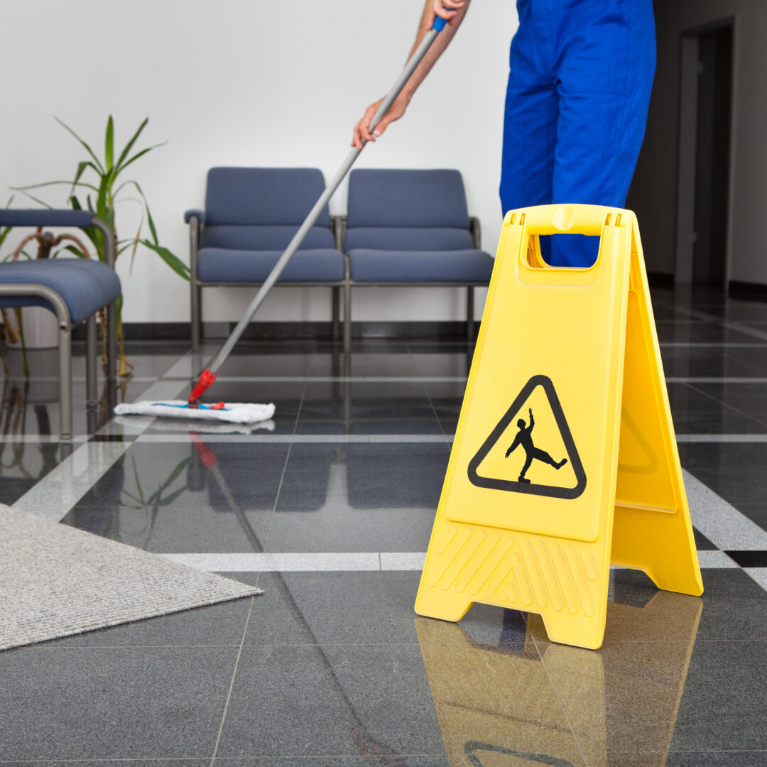 Close-up Of Man Cleaning The Floor With Yellow Wet Floor Sign