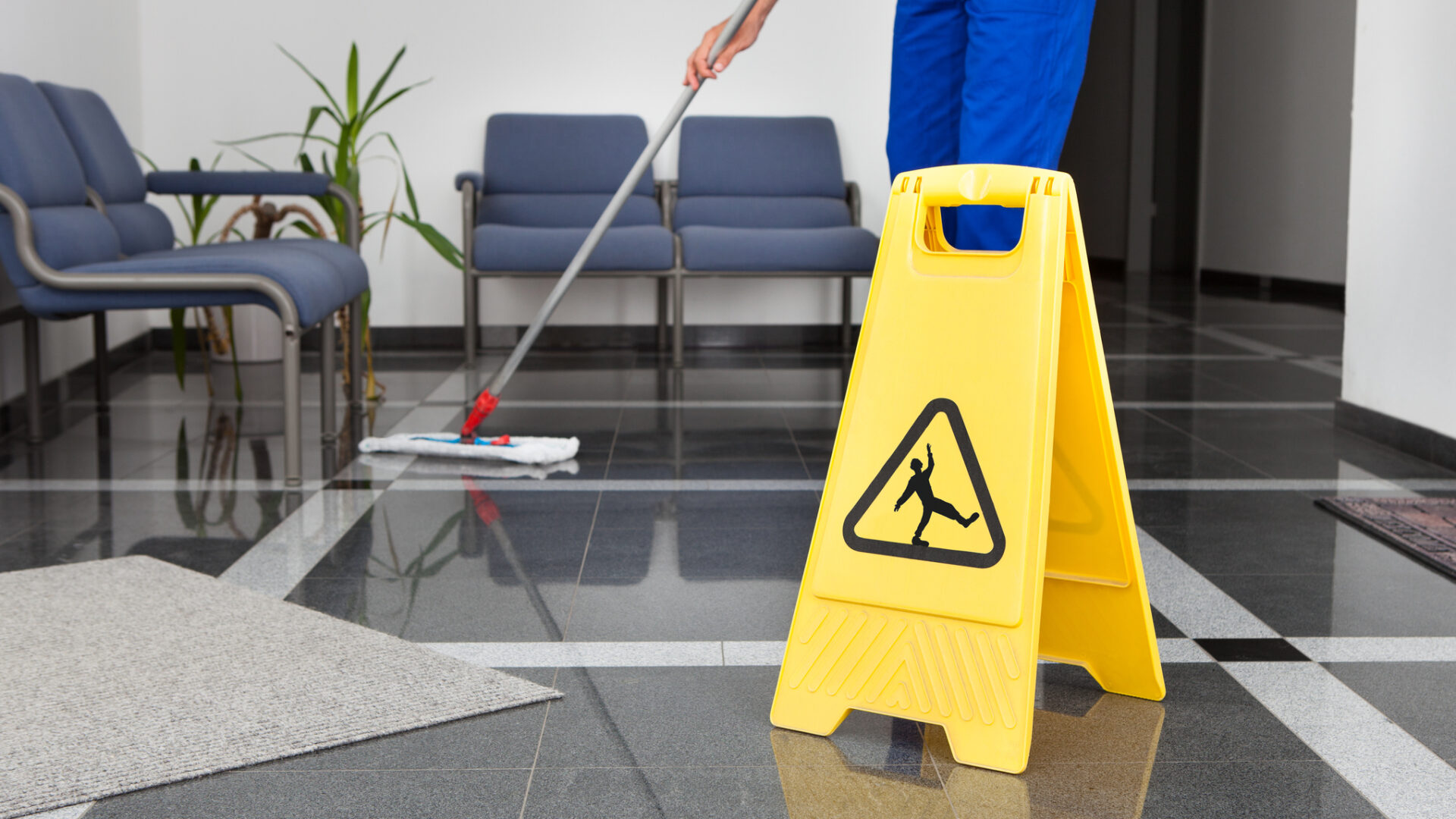 Close-up Of Man Cleaning The Floor With Yellow Wet Floor Sign
