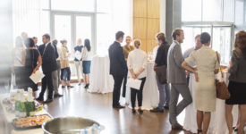 Group of conference participants standing in lobby of conference center, socializing during lunch break