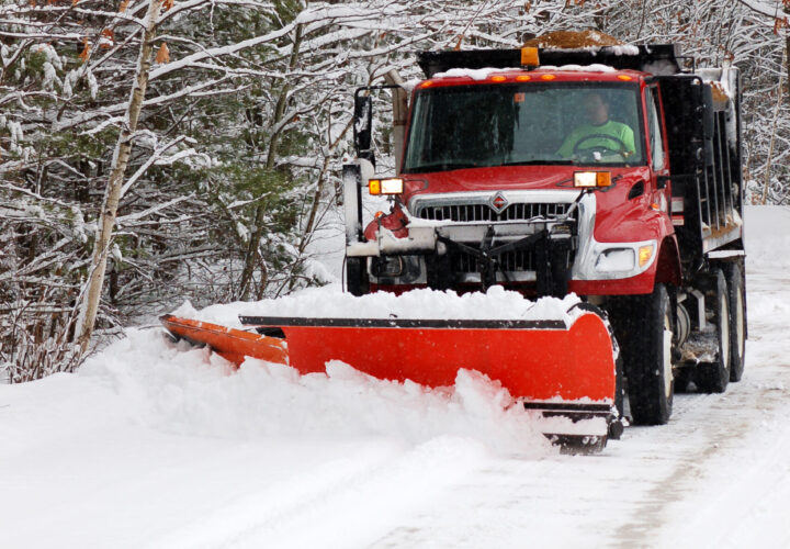 Red snow plow working a snow bank Plowing the snow on a rural road.